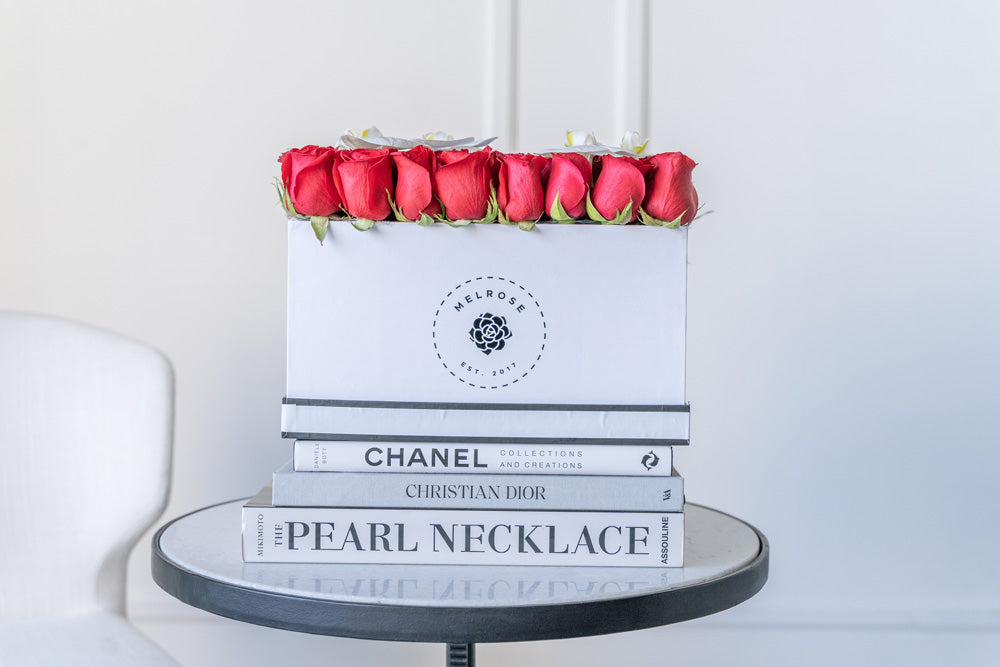 Rosas rojas en caja con flores de orquídea